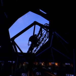 The Southern African Large Telescope dome's shutter is open and the nighttime sky reveals a few stars, the silhouette of the struts are clear.