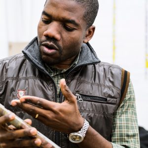 Herve Wabo looks at a rock sample in his hand
