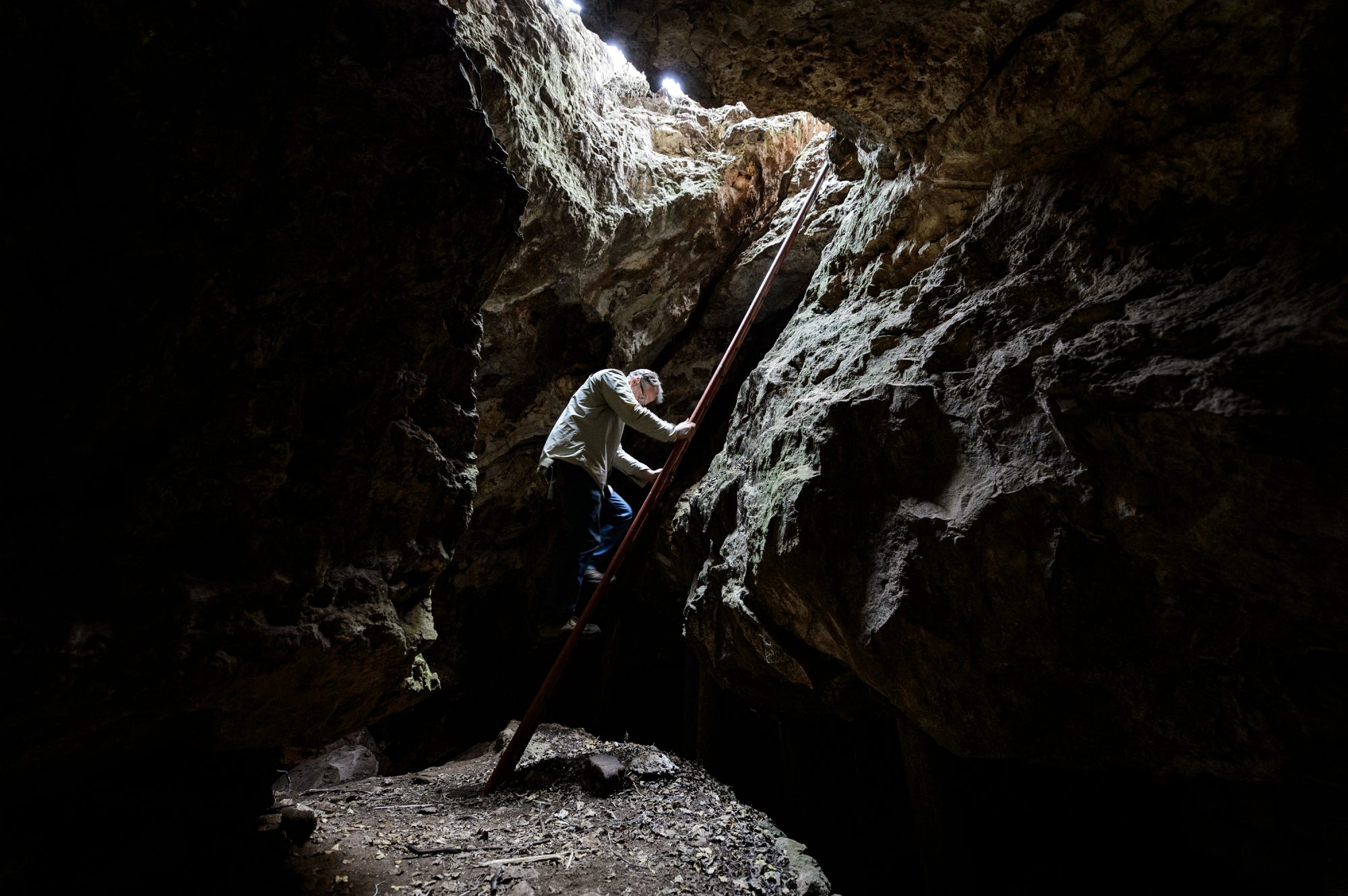 Travis Pickering descends a ladder into a cave
