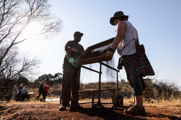 University of the Witwatersrand field assistant Andrew Moyagabo Phaswana and UW-Madison student Emmaleigh Grady use a sifting screen to sort for potential artifacts